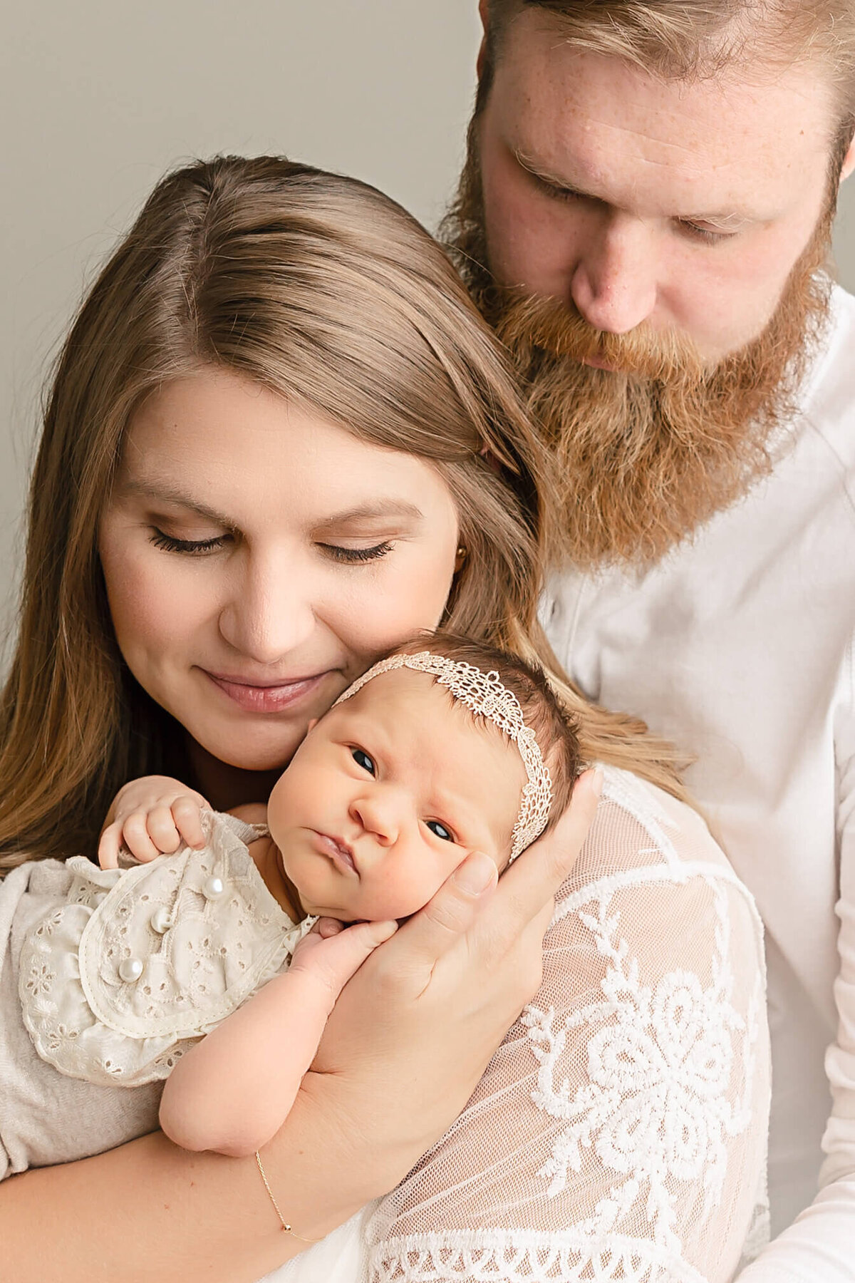 baby girl looking at camera with mom and dad looking down at her captured by Portland baby Photographer Ann Marshall