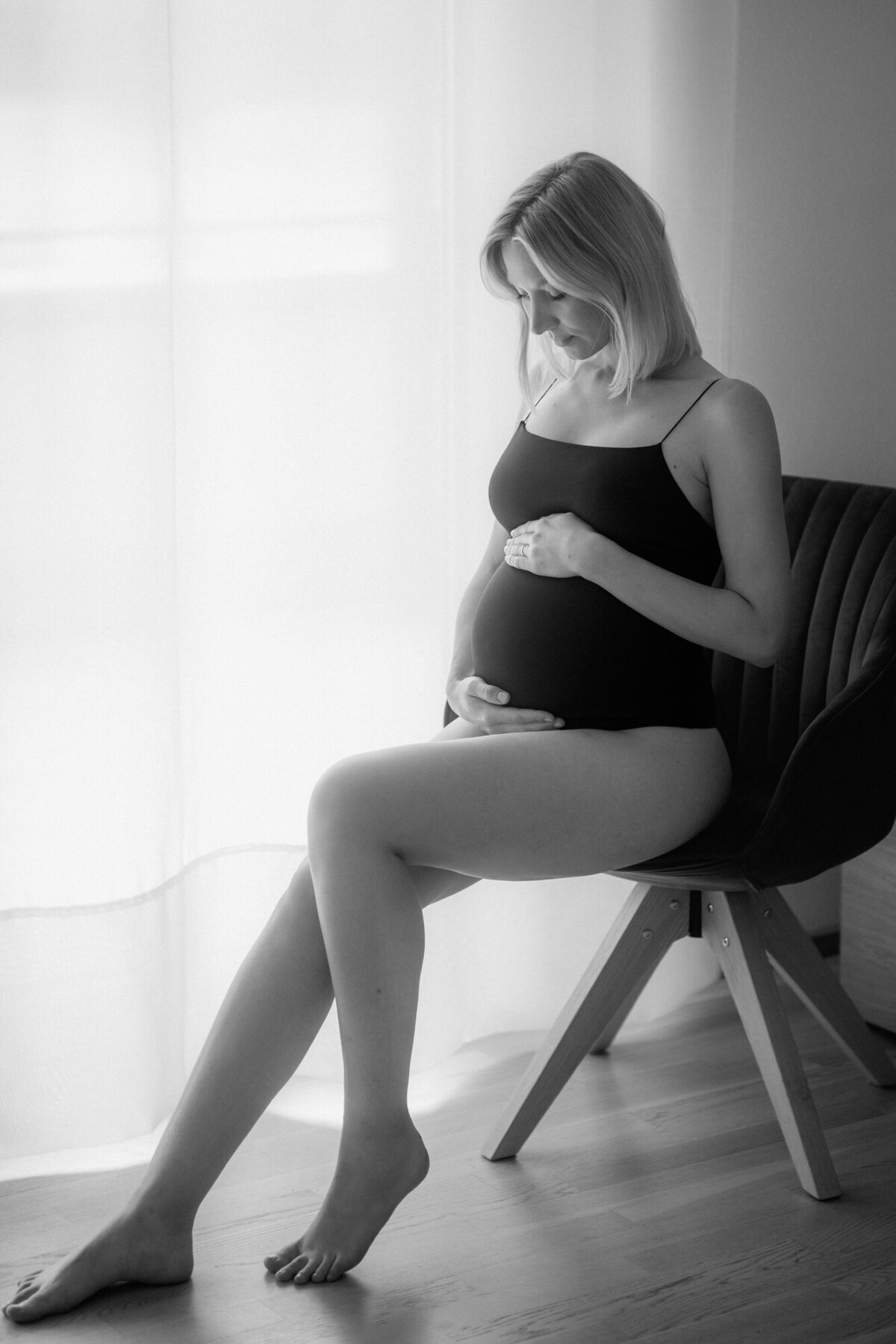 Maternity portrait of an expecting woman sitting on a chair.