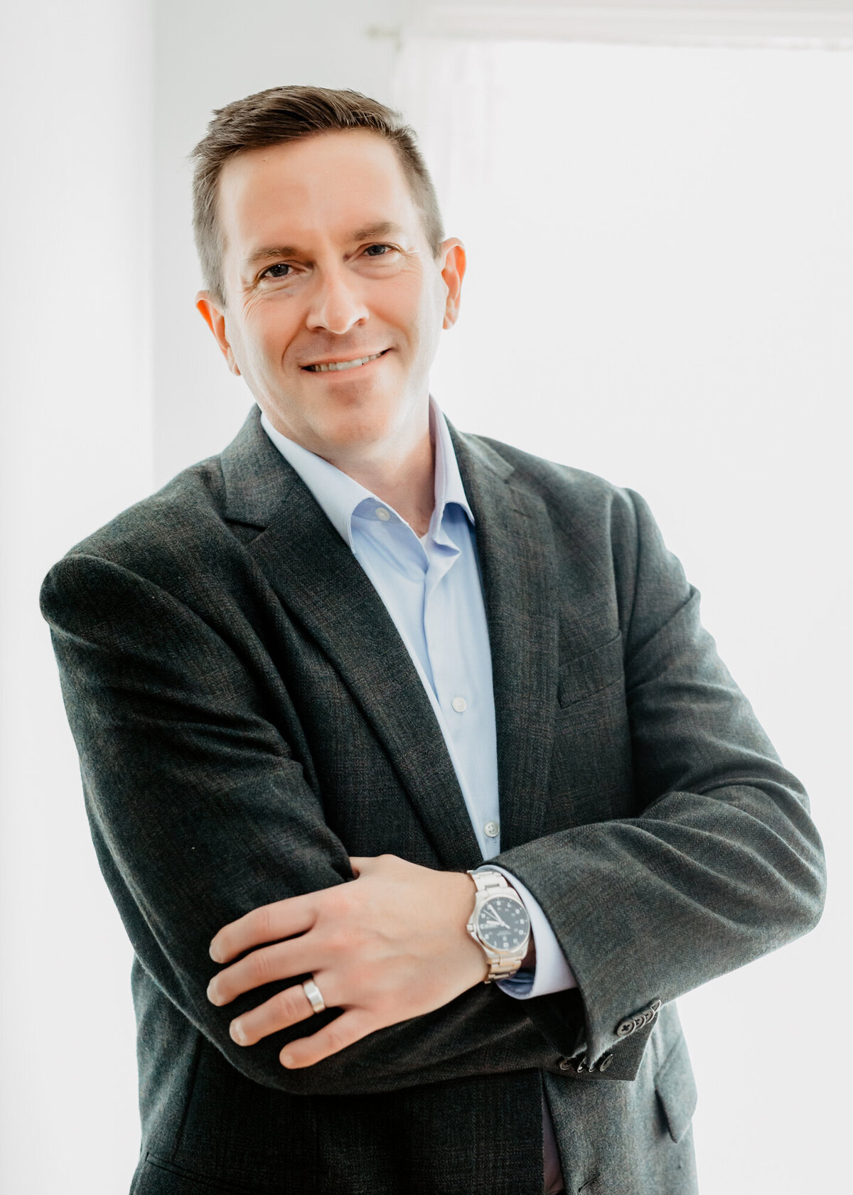 Male corporate headshot client standing with arms crossed and smiling
