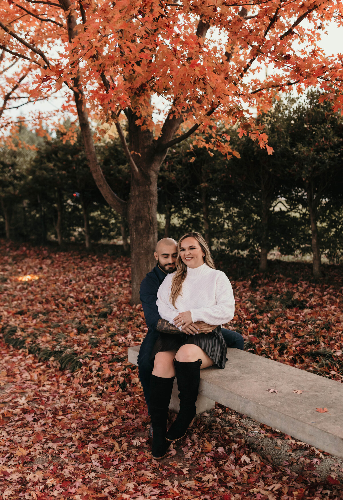couple sitting on a bench with leaves around