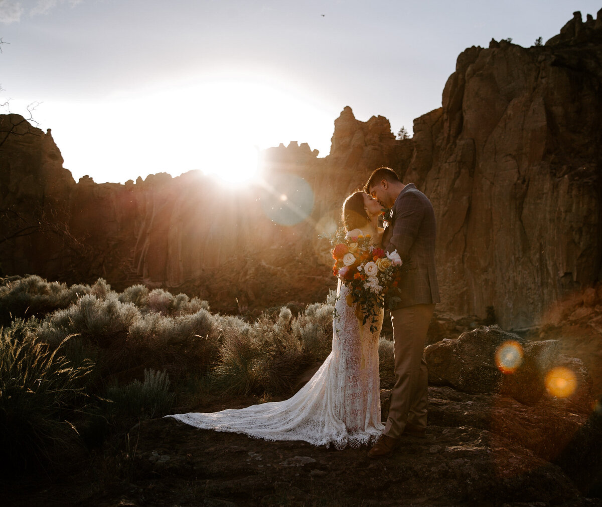 Couple kissing with a bouquet in Smith Rock elopement