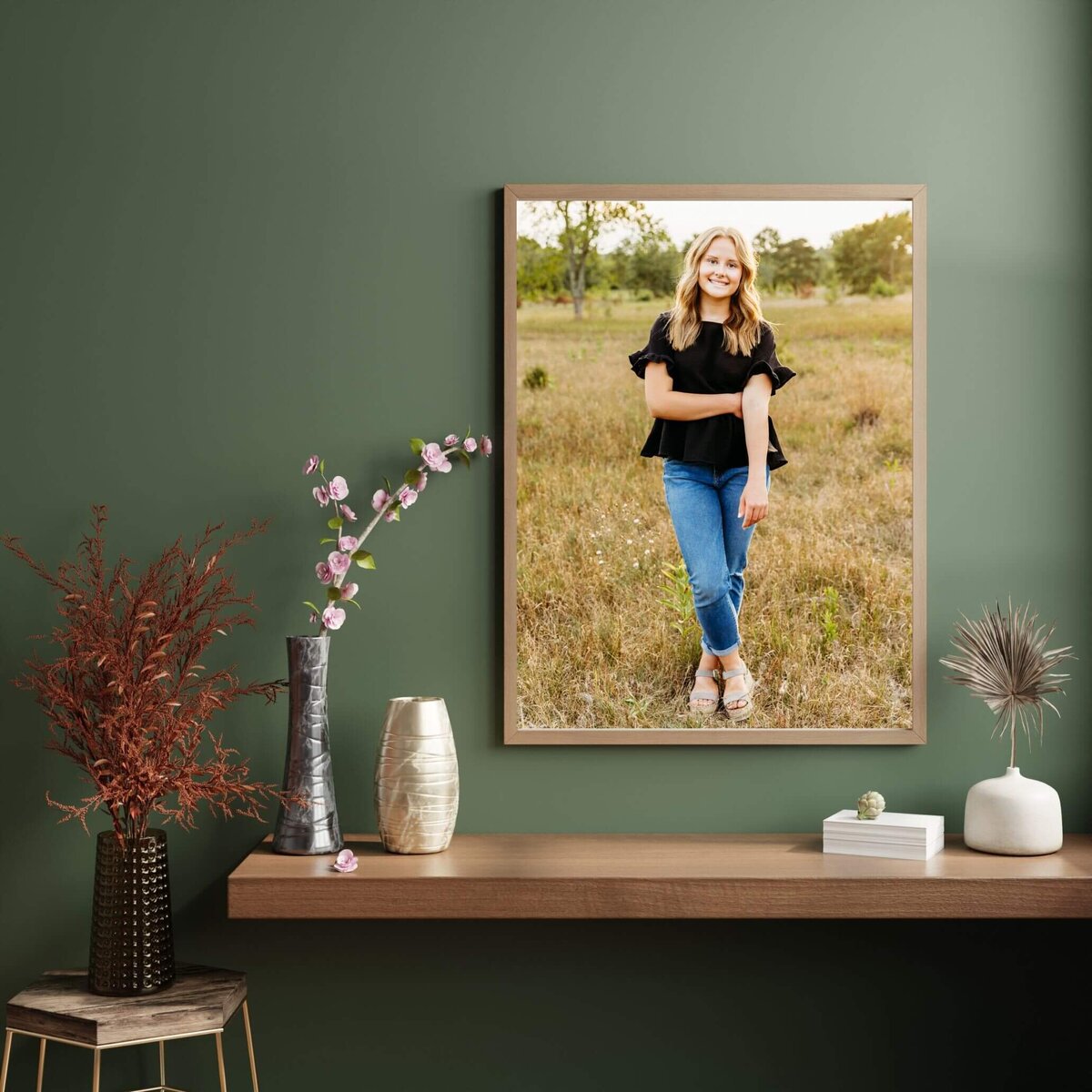 earthy green wall with an Oshkosh high school senior photo hanging above a wooden shelf