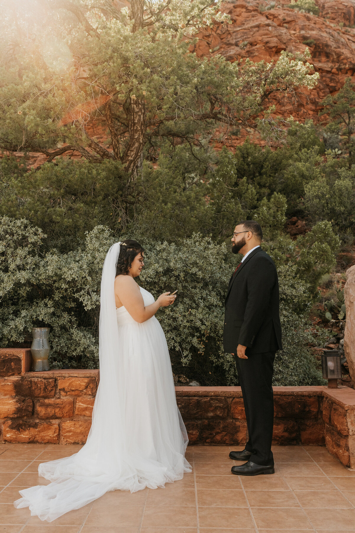 A wedding couple standing together as one reads a note 