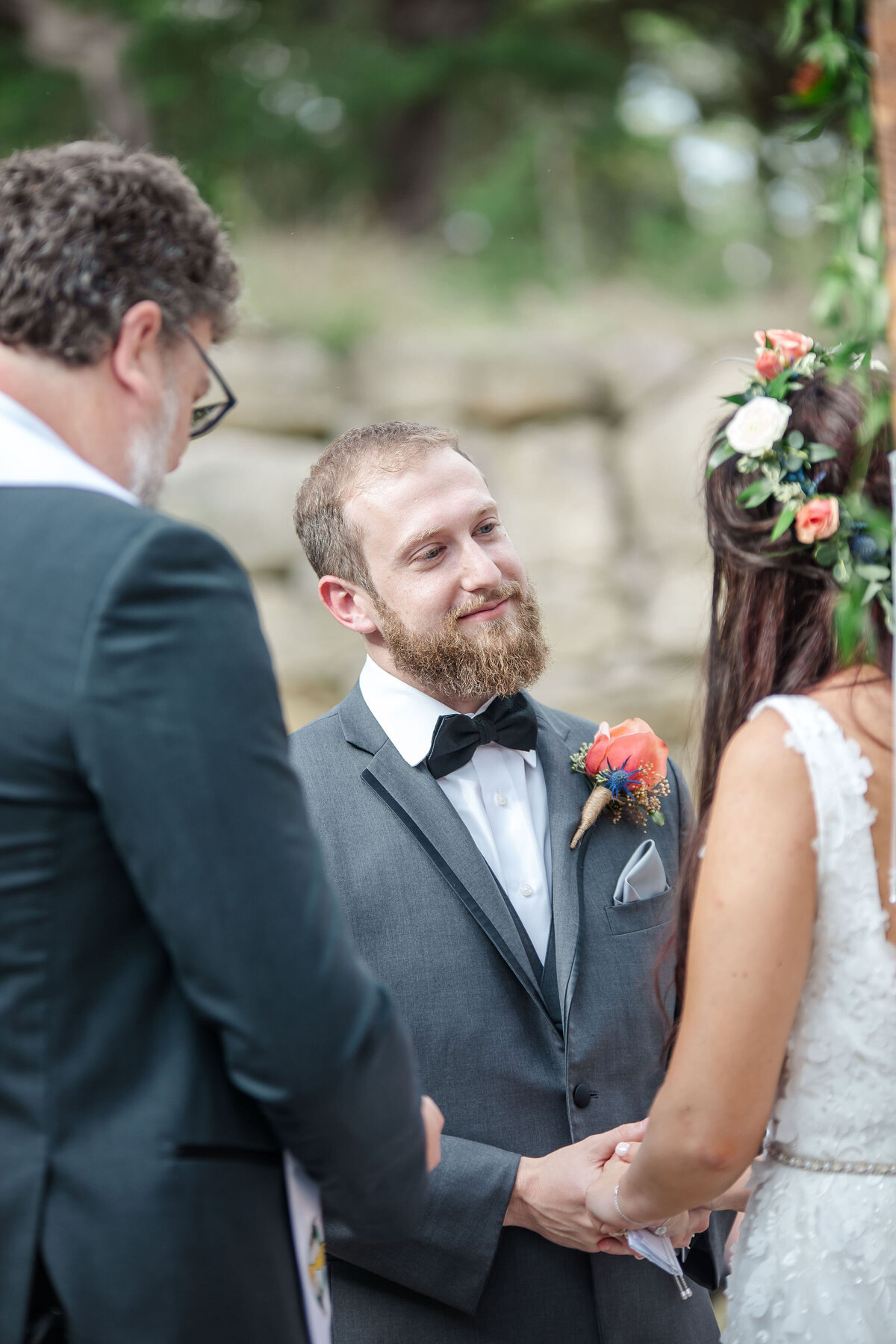 groom gazes at bride wearing flower wreath headpiece