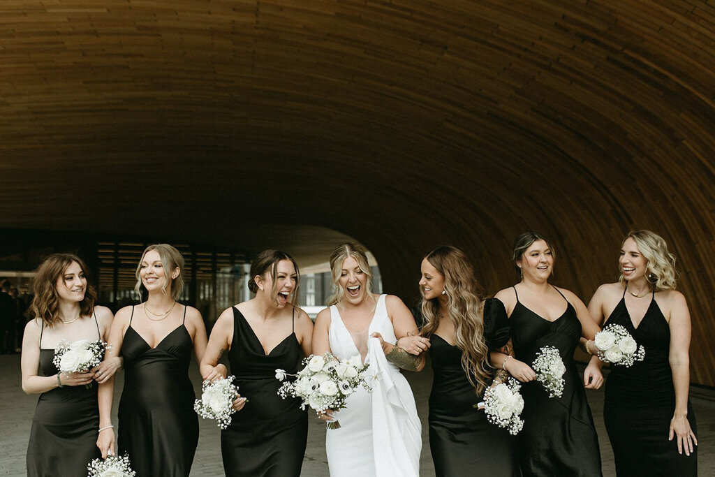 Bride walking with bridesmaids, satin black dresses, by Court Amber Photography, joyful and adventurous wedding photographer in Calgary, Alberta. Featured on the Bronte Bride Vendor Guide.