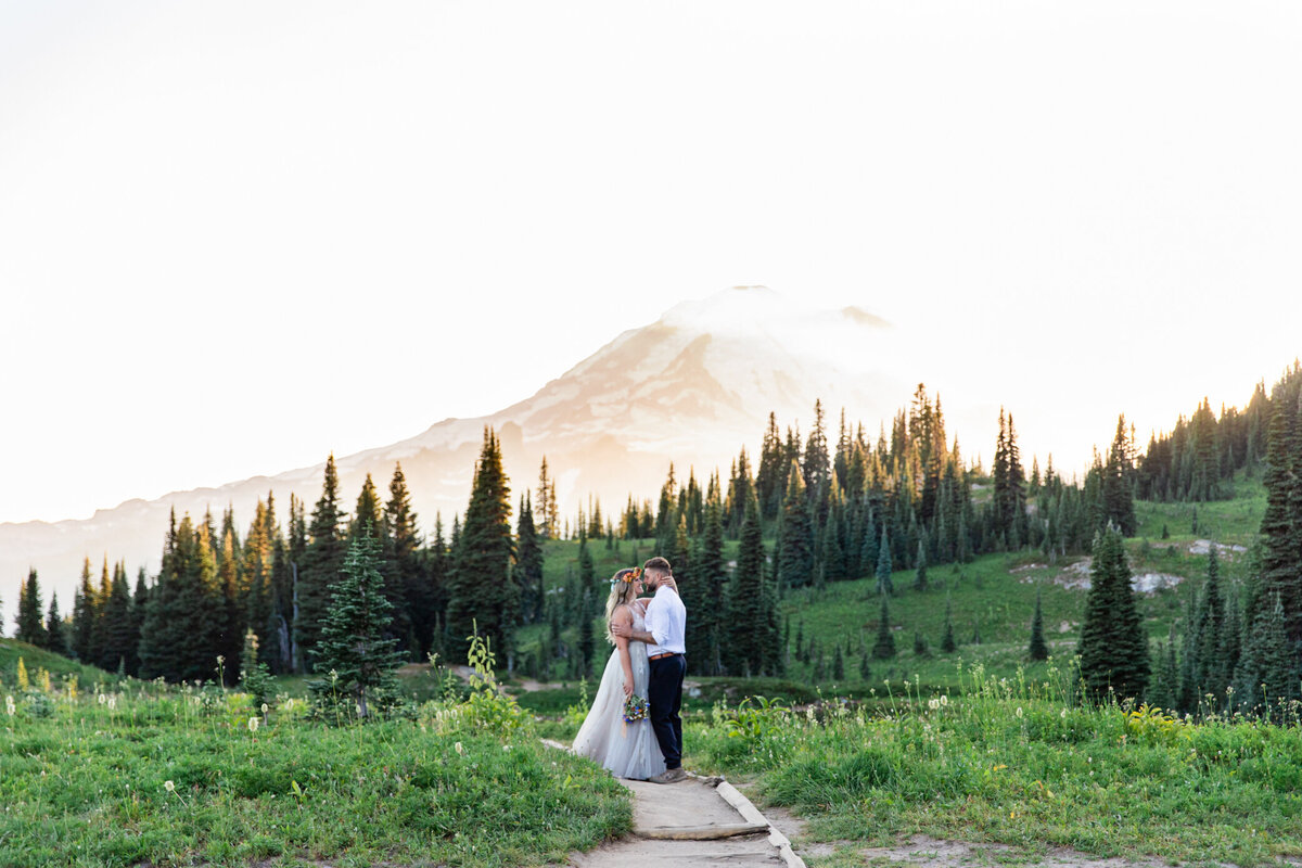 bride and groom snuggle with a mountain in the background