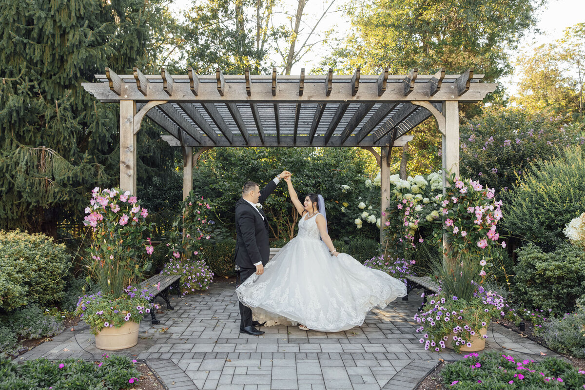 The Palace at Somerset Park | Groom spinning bride by gazebo with flowing dress and flowers during wedding | Somerset, New Jersey