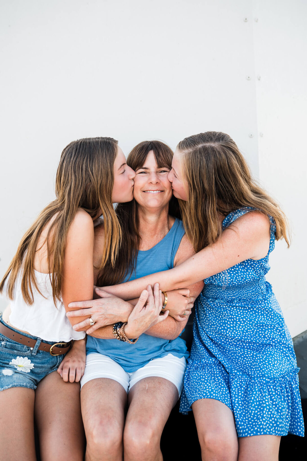 two daughters kissing mom on cheek