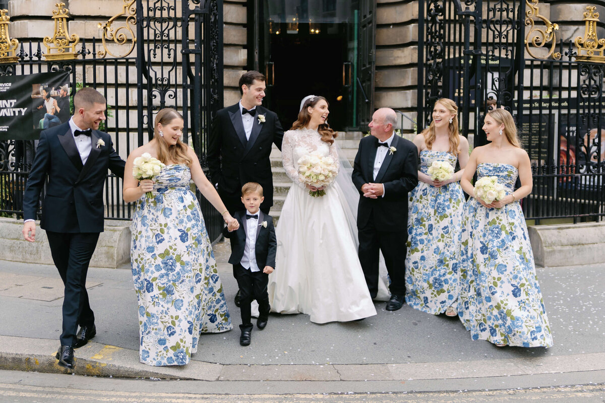 bride and groom walk laughing with their bridesmaids and groomsmen through the streets of london after their chic city wedding ceremony