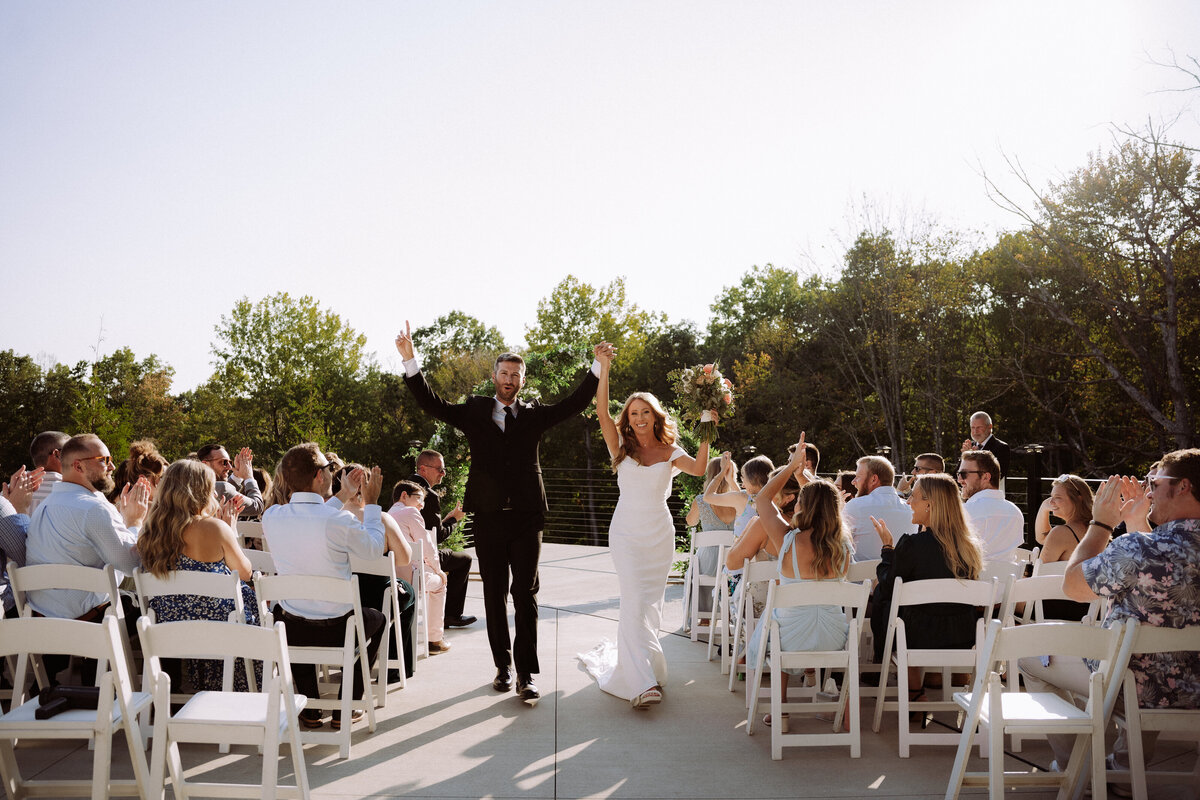 happy newly weds walking down aisle at outdoor wedding venue