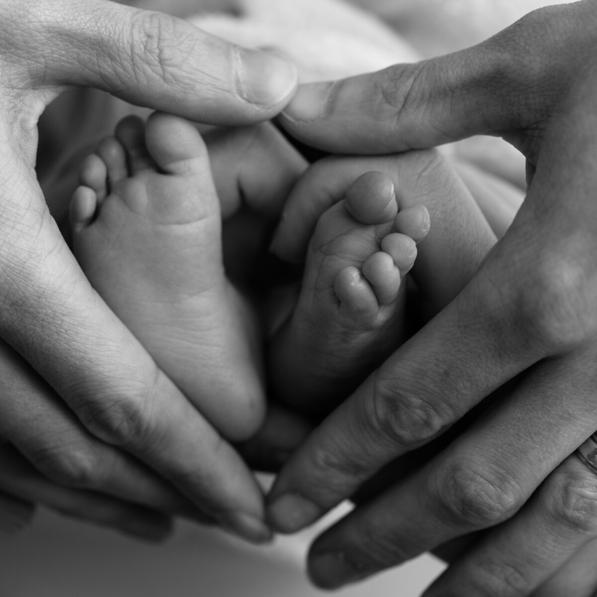 Cradled by love—this macro shows two hands gently encircling baby’s feet, symbolizing the beginning of family.