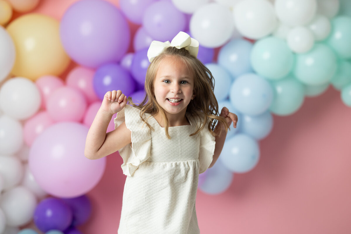 Little girl celebrating her birthday with colorful balloons, full of joy and excitement, photographed by Victoria Lee Photography in Canton, GA.