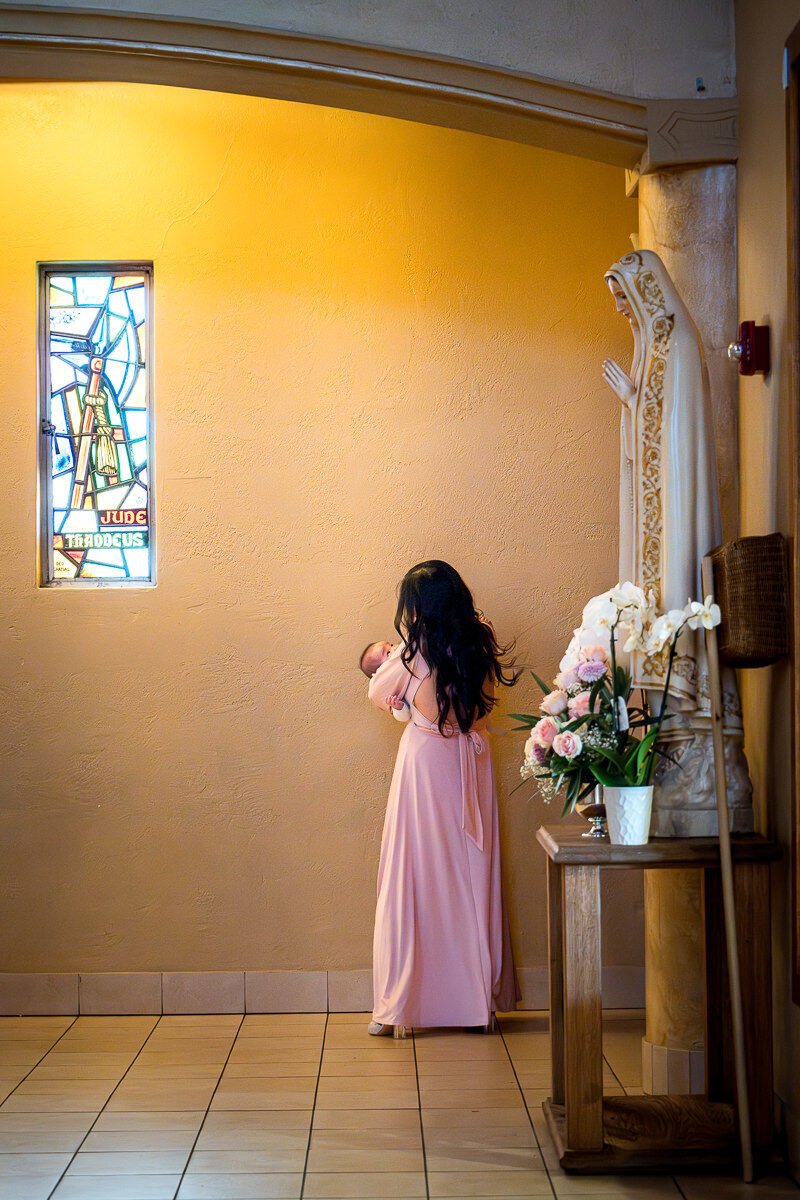 A tender moment as a mother gently soothes her baby during a heartfelt wedding ceremony at the historic Queen of All Saints Church in Concord, California.