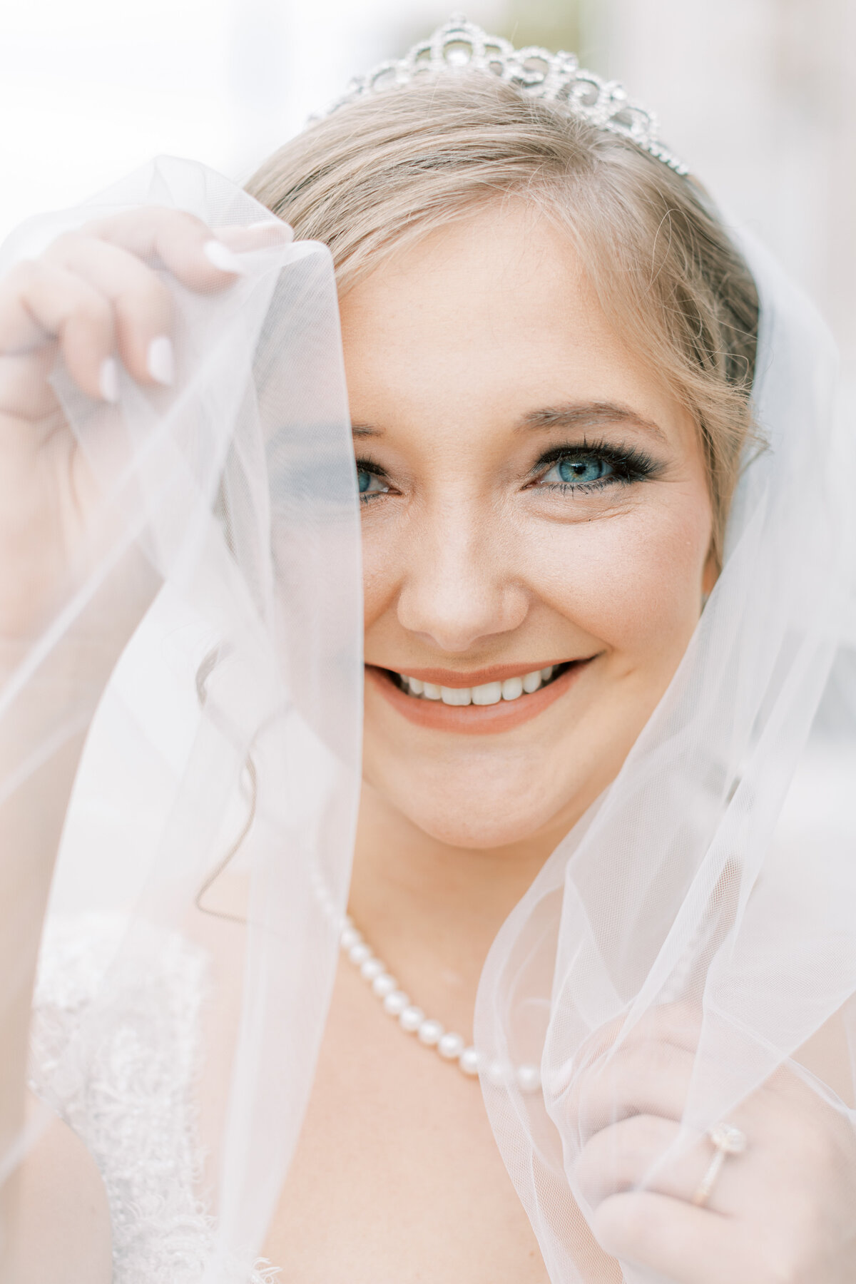 A bride covers up half of her face with the veil.
