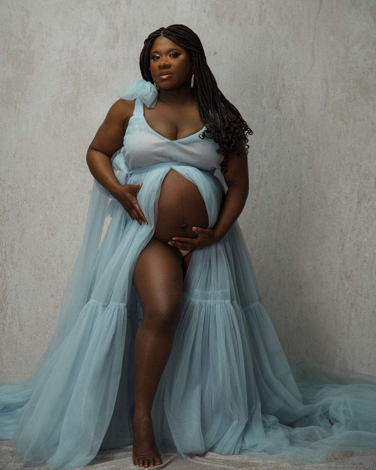 Pregnant woman in light blue long maternity dress showing tummy