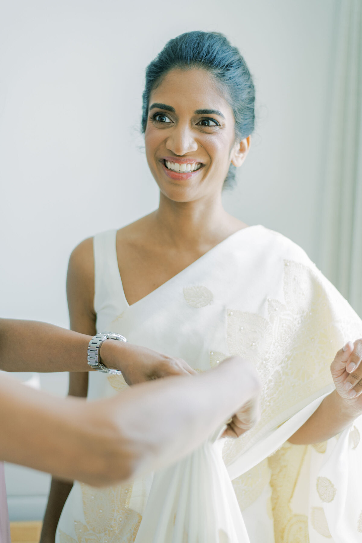 Bride having her dress tied up for her indian ceremony.