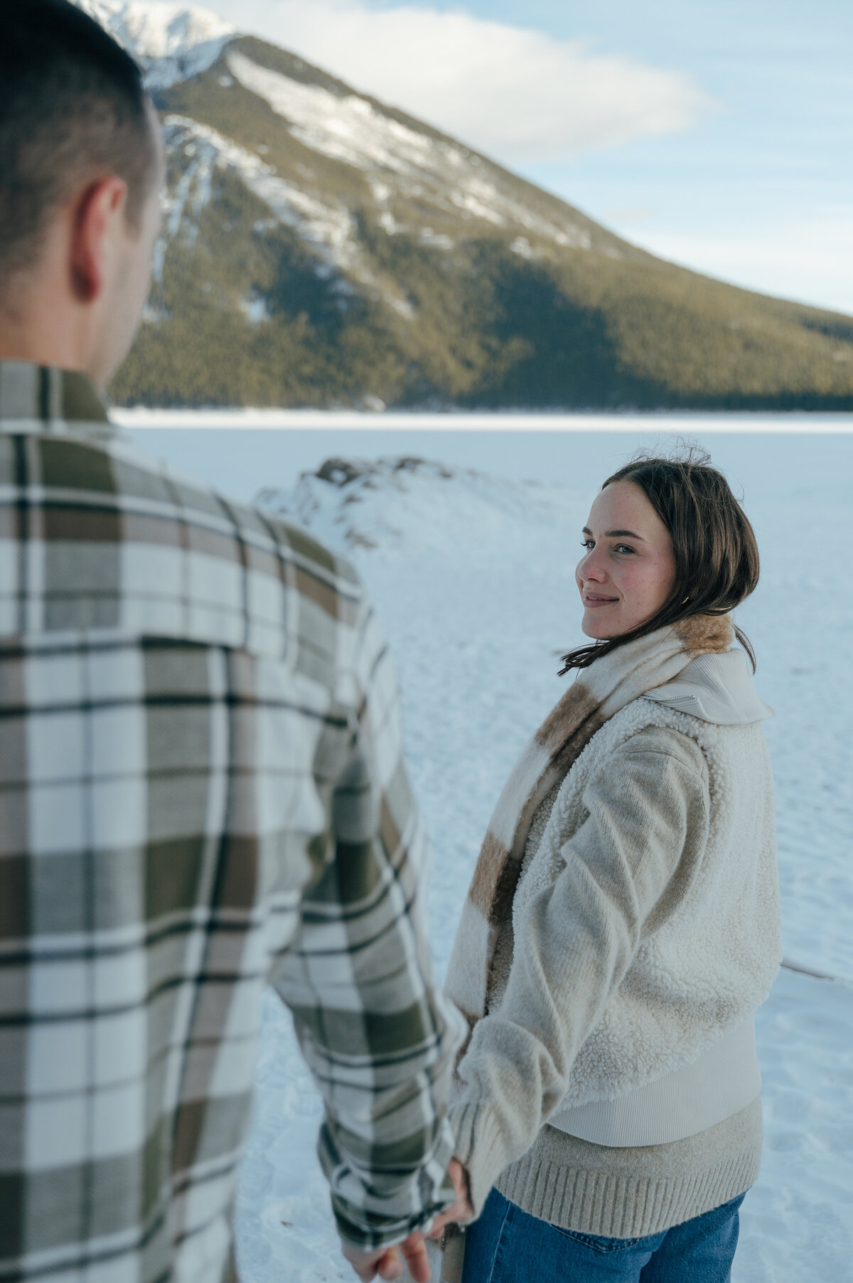 Woman smiling at her partner with snow-covered mountain behind in Banff.