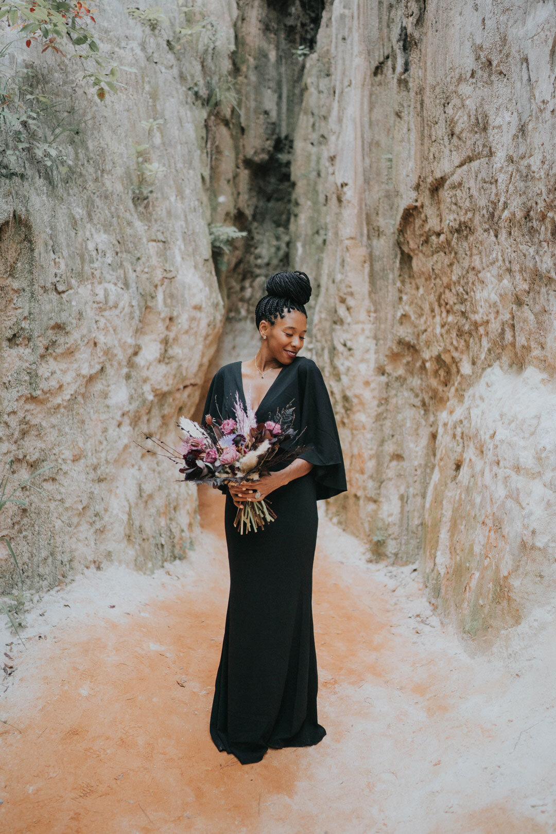 Black woman in black dress holding a pink bouquet