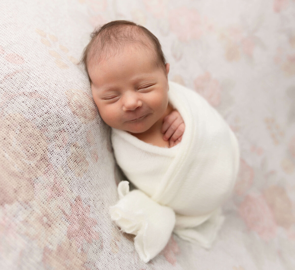 Wrapped baby newborn picture on a pink flower backdrop