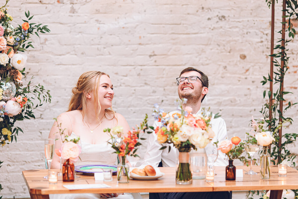 A couple shares laughs during speeches at their wedding at The Joinery in Chicago