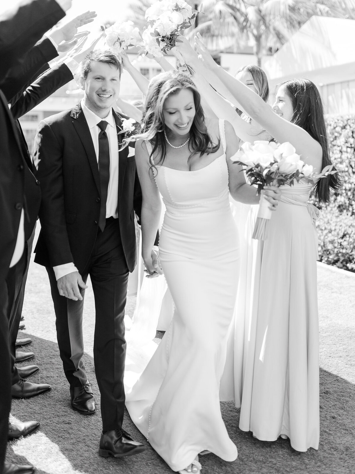 Bride and groom smiling as they exit their wedding ceremony surrounded by friends
