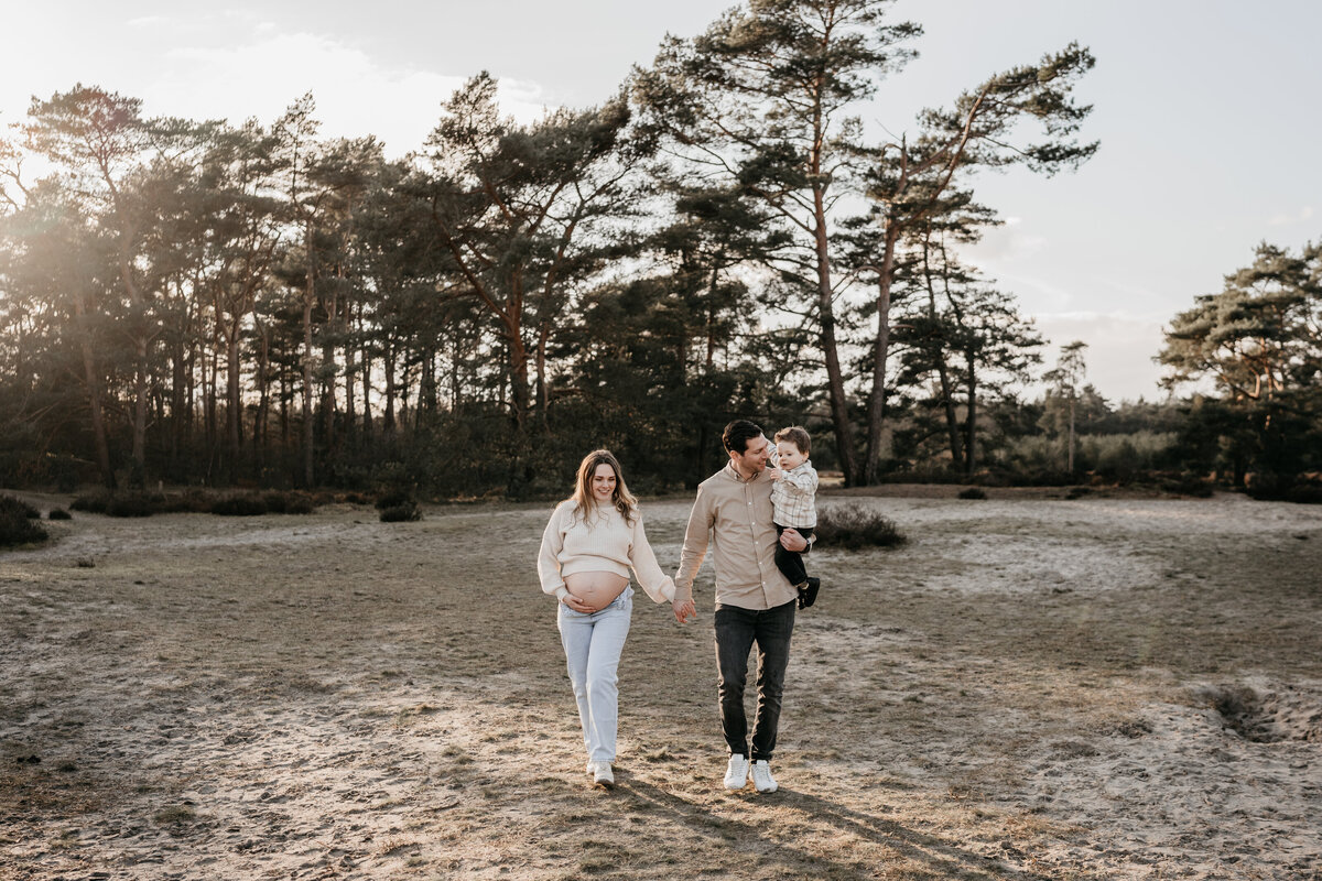 Gezin loopt hand in hand bij een zwangerschapsshoot in de Soesterduinen.