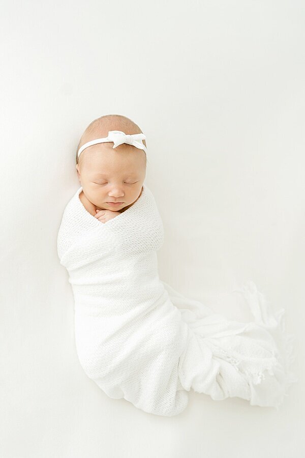 Baby girl swaddled in white with bow for Louisville Portrait Photography session