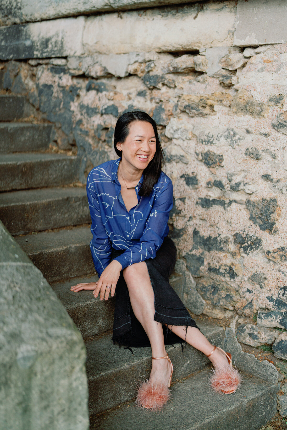 Kim-Trang smiles while sitting cross legged on old Parisian steps