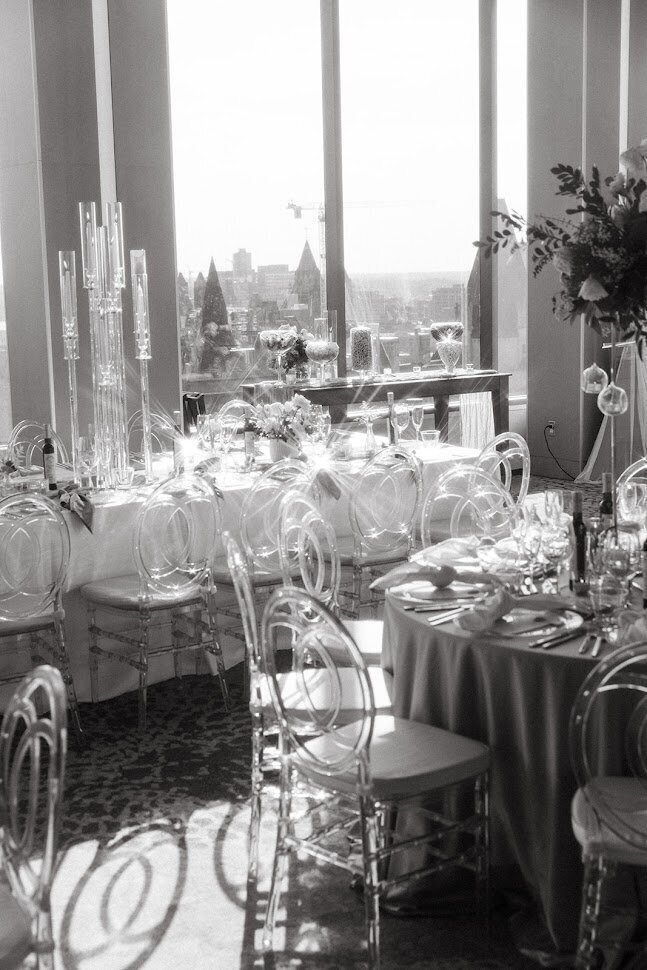 This black and white photo showcases both round and rectangular table designs for a wedding, set against a stunning city backdrop. The contrasting table shapes create visual interest, highlighting our ability to blend style with functionality. Ideal for couples seeking unique decor solutions for their Ottawa events, this image reflects our commitment to beautiful, cohesive wedding experiences.