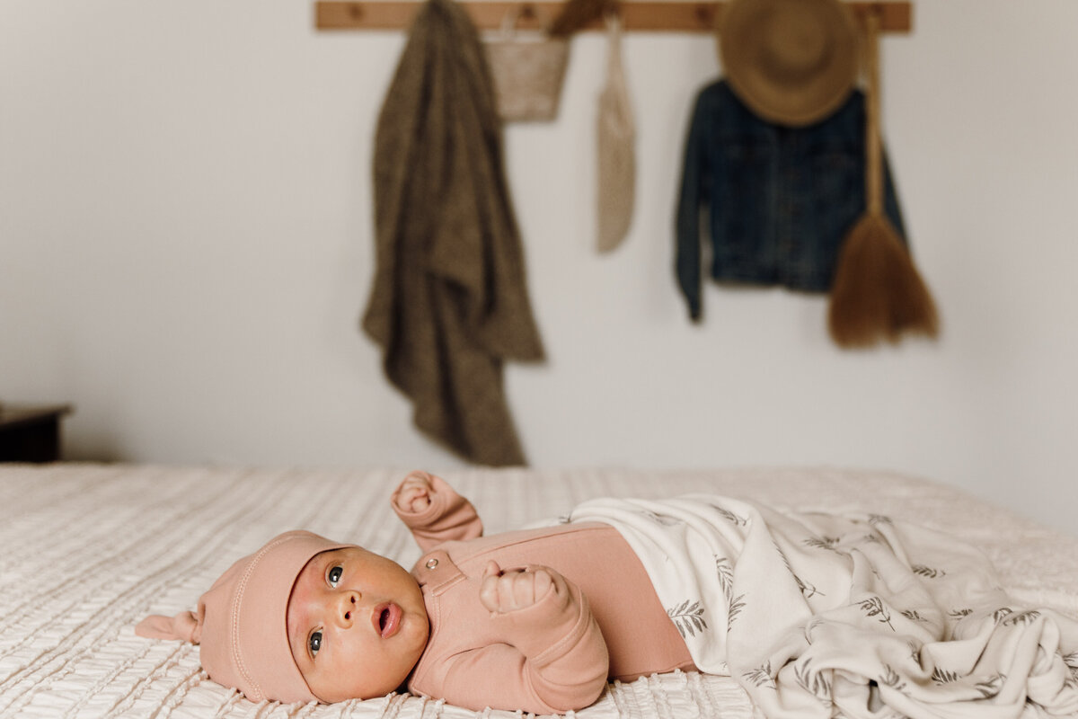 Flat lay of baby clothing and accessories styled on a neutral background.
