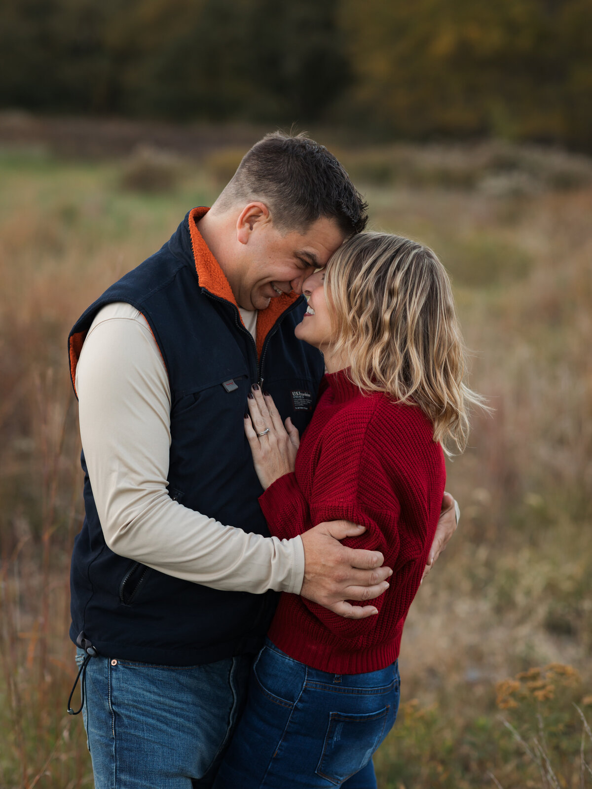 husband and wife hugging for family photos in field