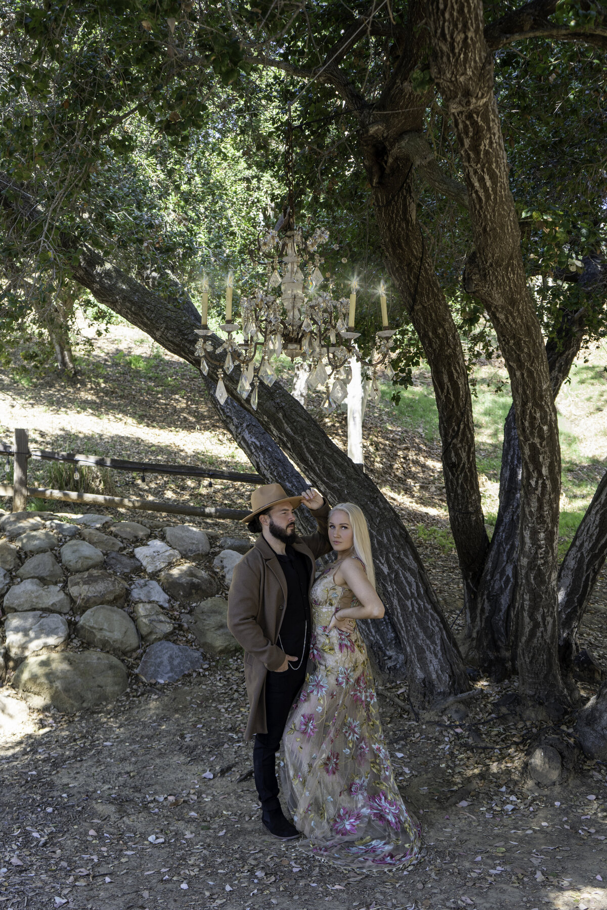 Engaged couple at the Malibu mountains during morning light the man wearing cowboy attire and the woman a colored lace Claire Pettibone gown