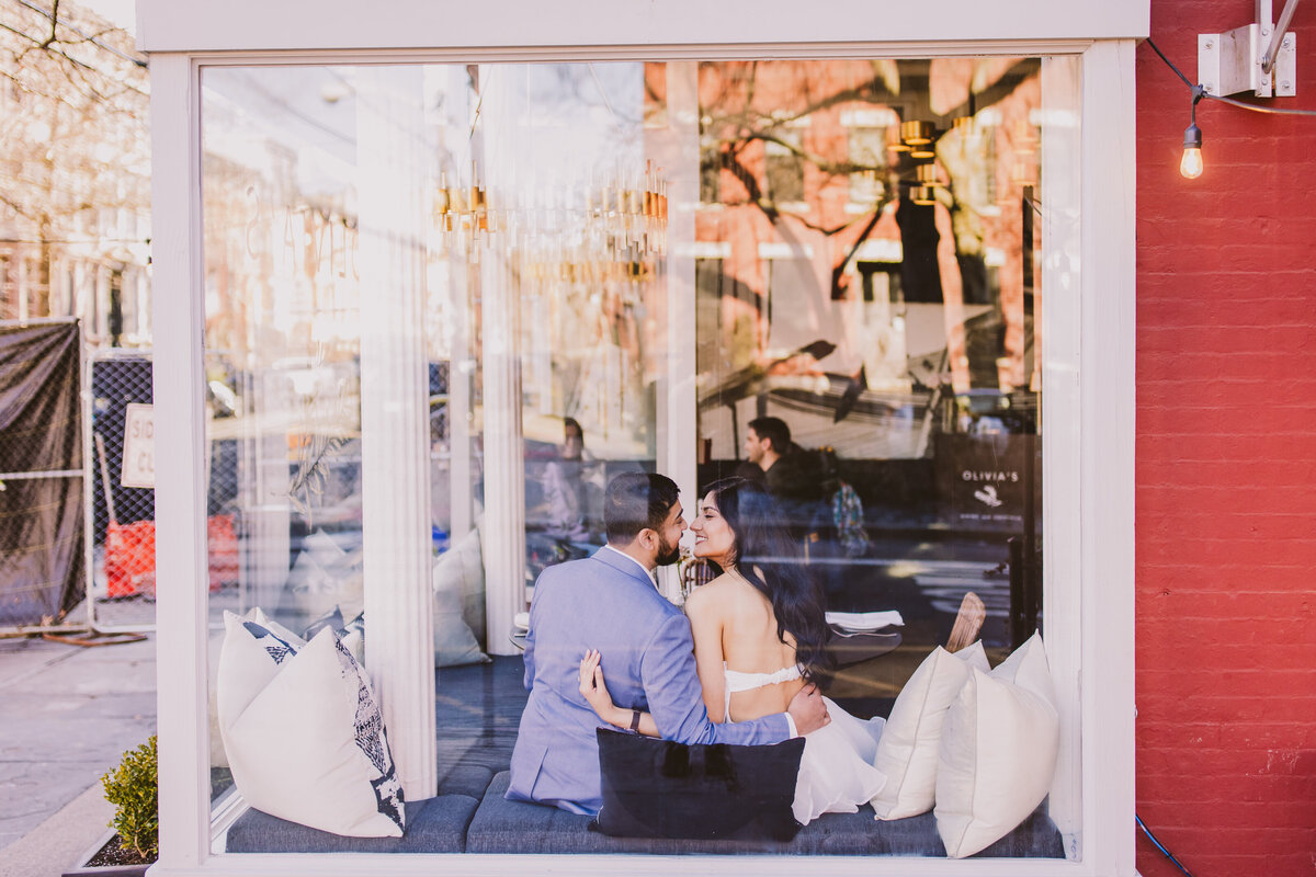 An engaged couple share a moment inside a restaurant called olivia's in hoboken nj