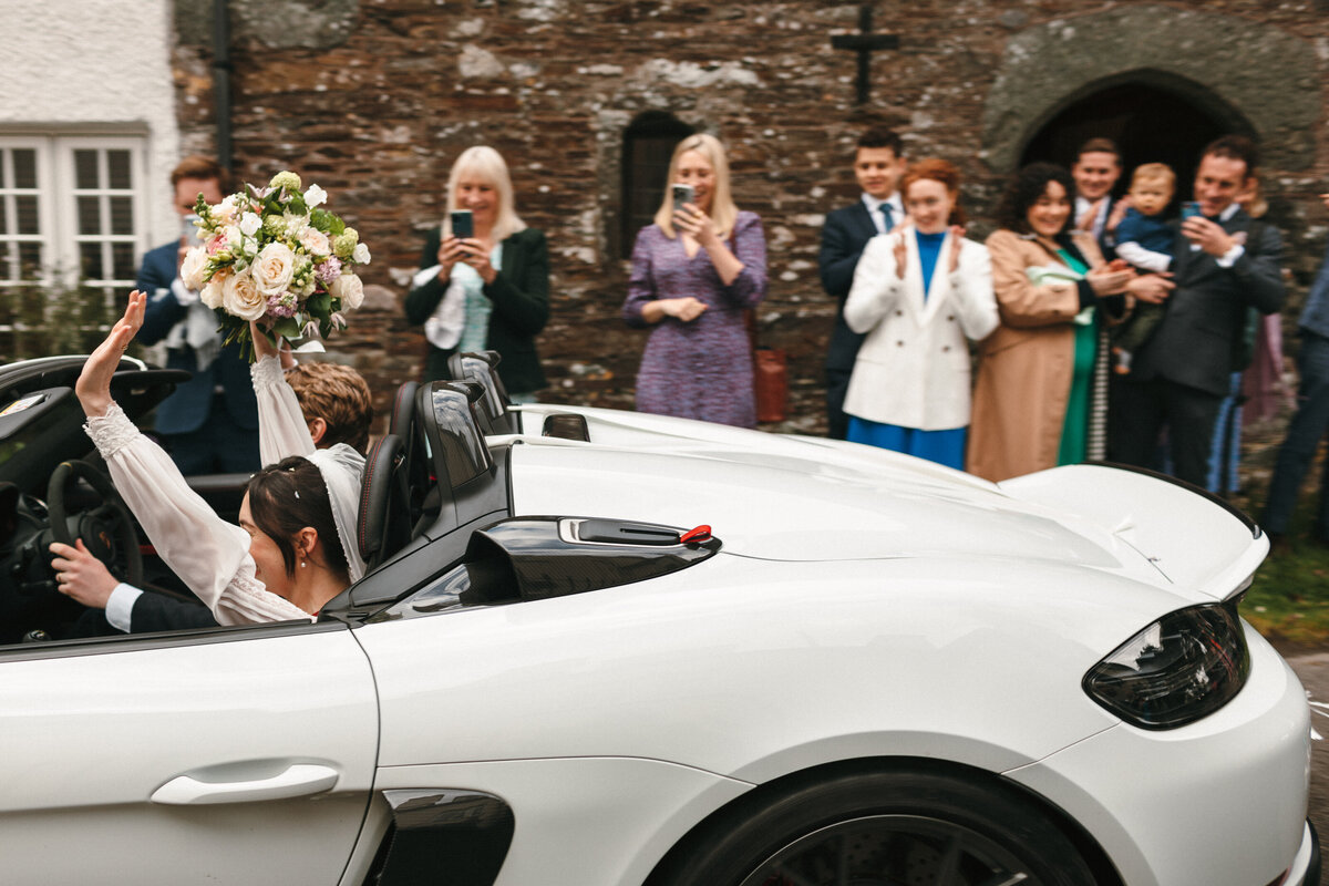 Bride and groom exit the church in a Ferrari 