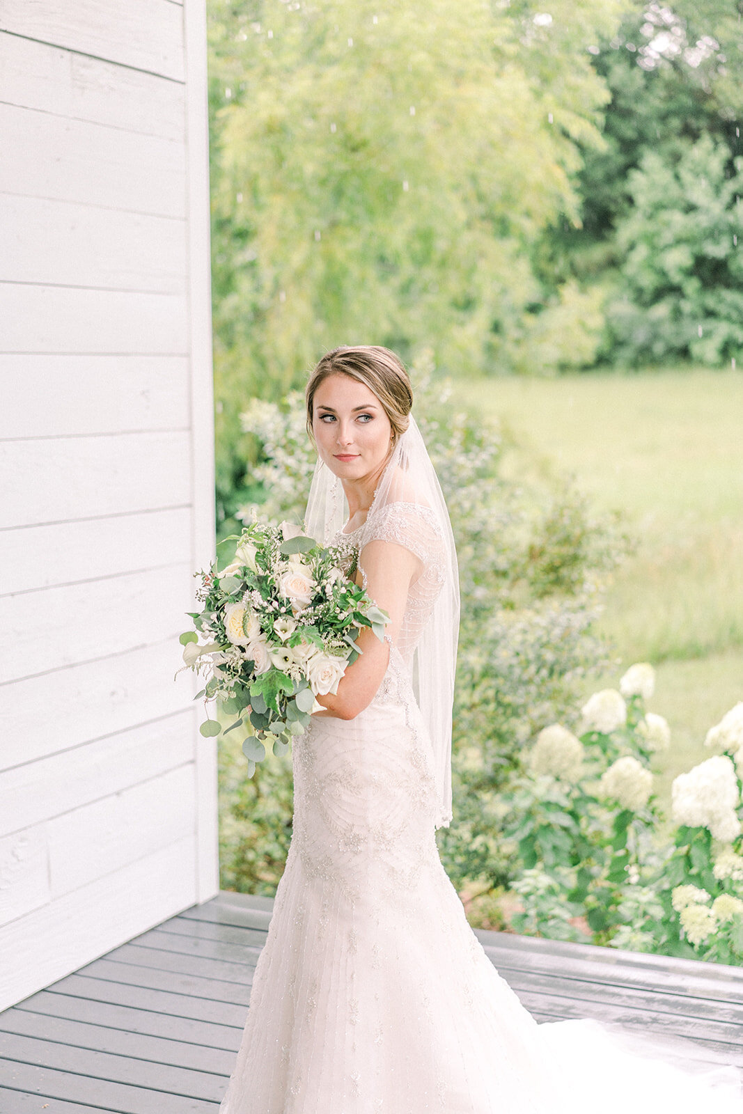 bride holding a bouquet of white flowers while looking off into the distance