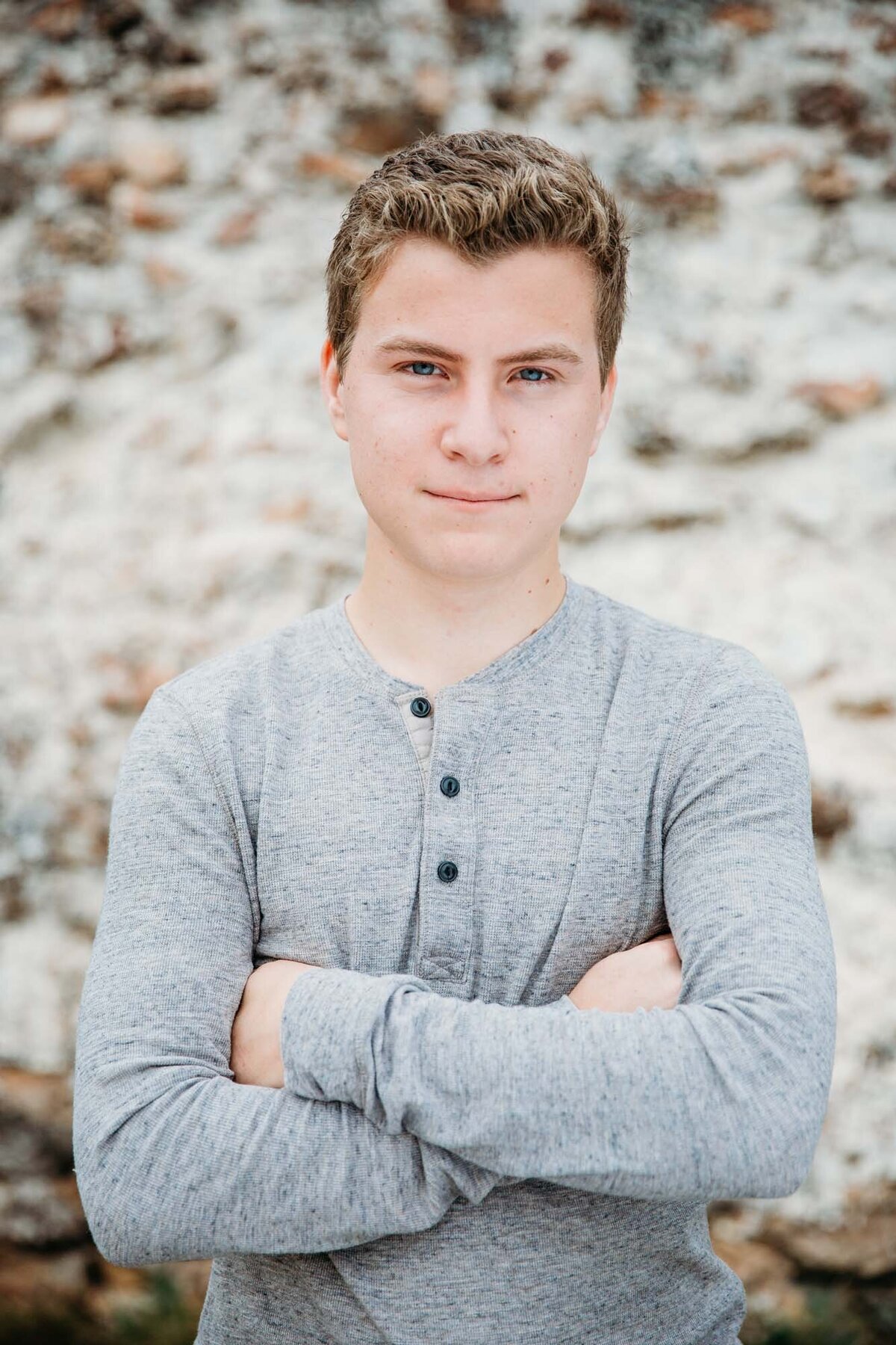 Dramatic senior portrait of a guy in a gray shirt.