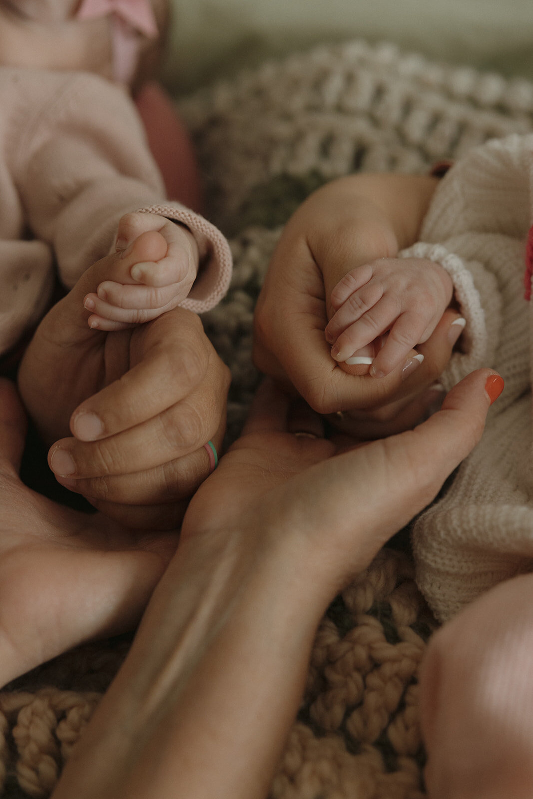 close up of parents and newborn twin's hands 