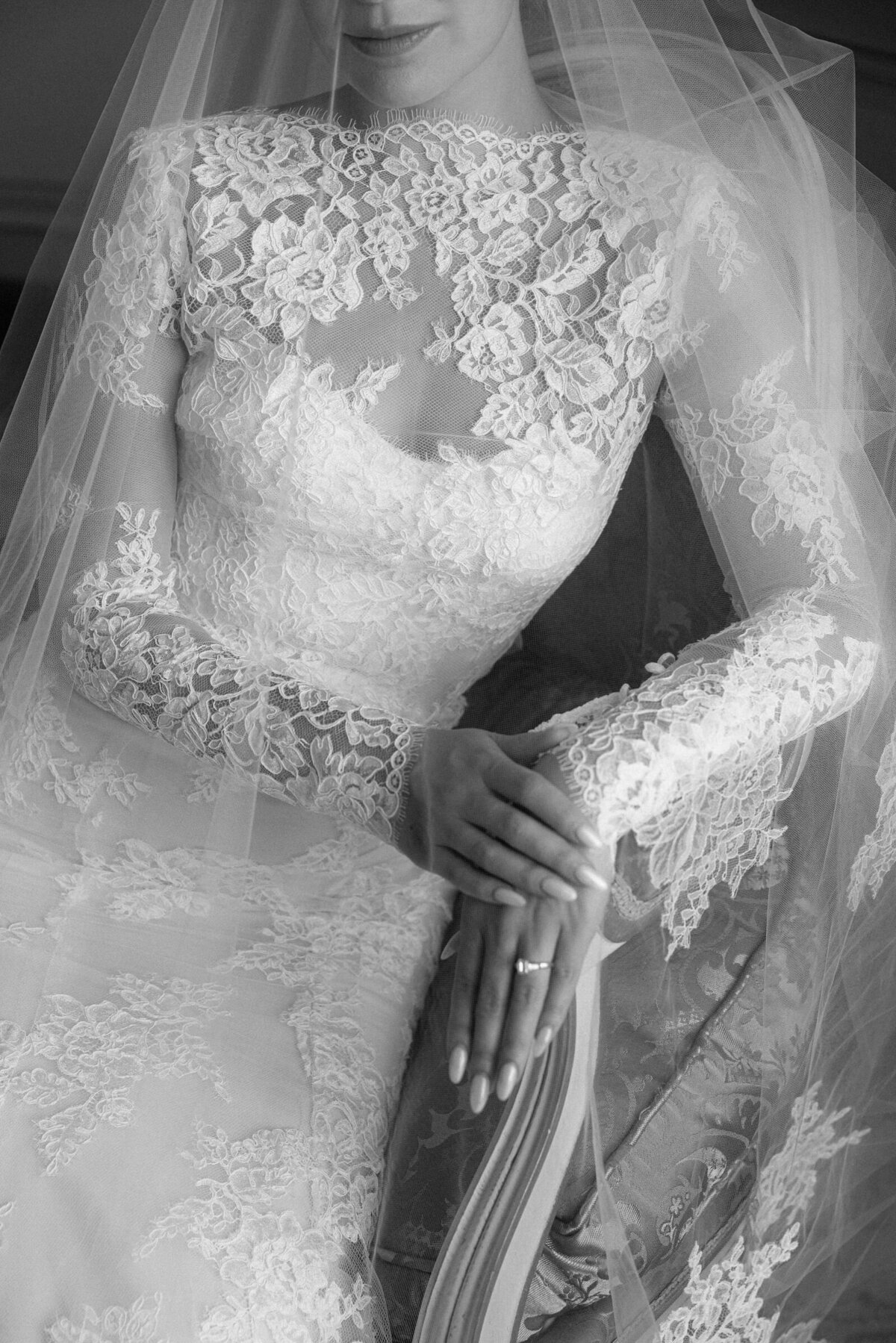 detail shot of the bridal's dress lace and the wedding ring on bride's hand.