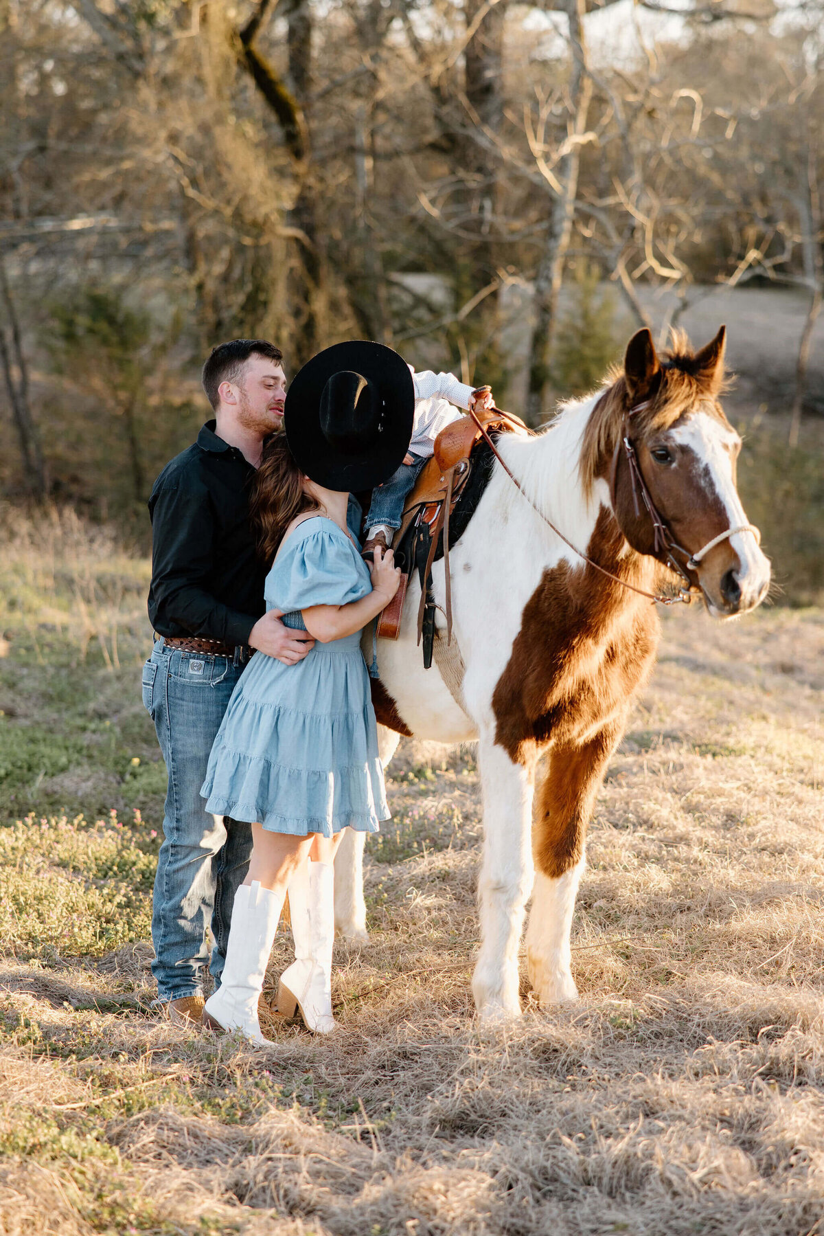 toddler on horseback leaning over to kiss his momma