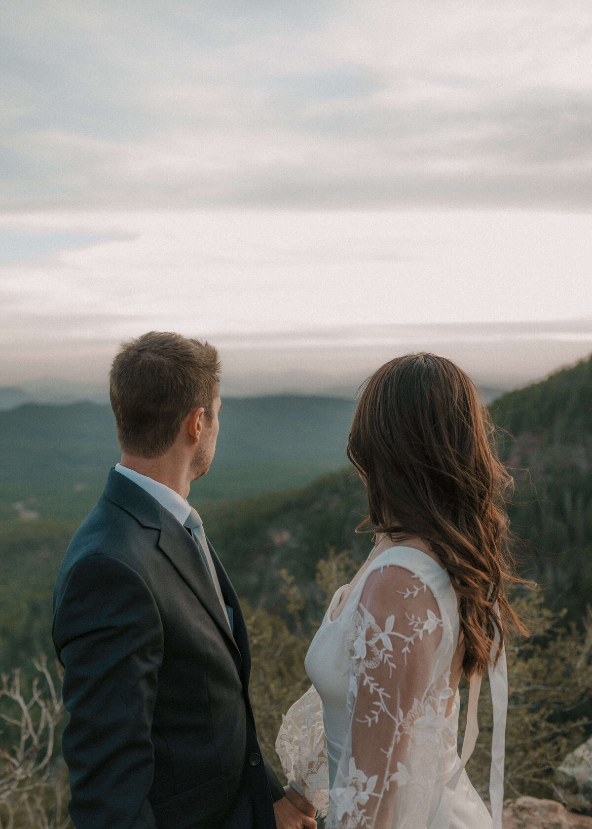 bride and groom facing each other with heads turned as they look at scenic mogollon rim in payson, arizona