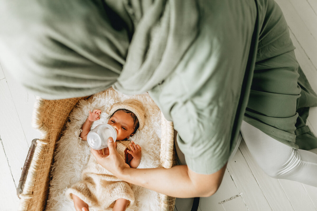Infant photographer capturing a newborn baby sleeping in crib.
