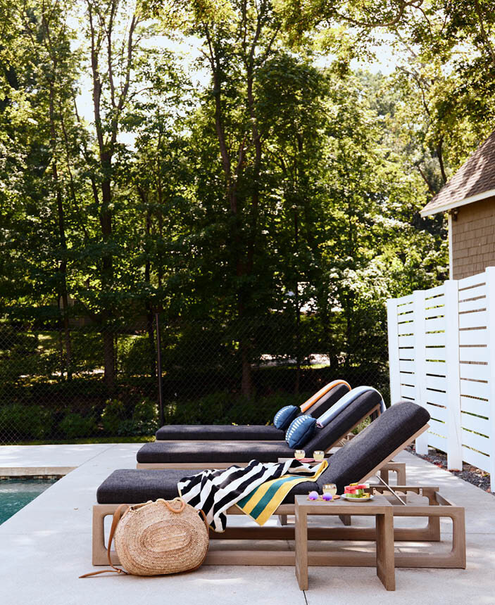 Relax by the pool in a historic Hingham home with coordinating weatherproof wood chaise lounges and small side tables, perfect for an afternoon dip.