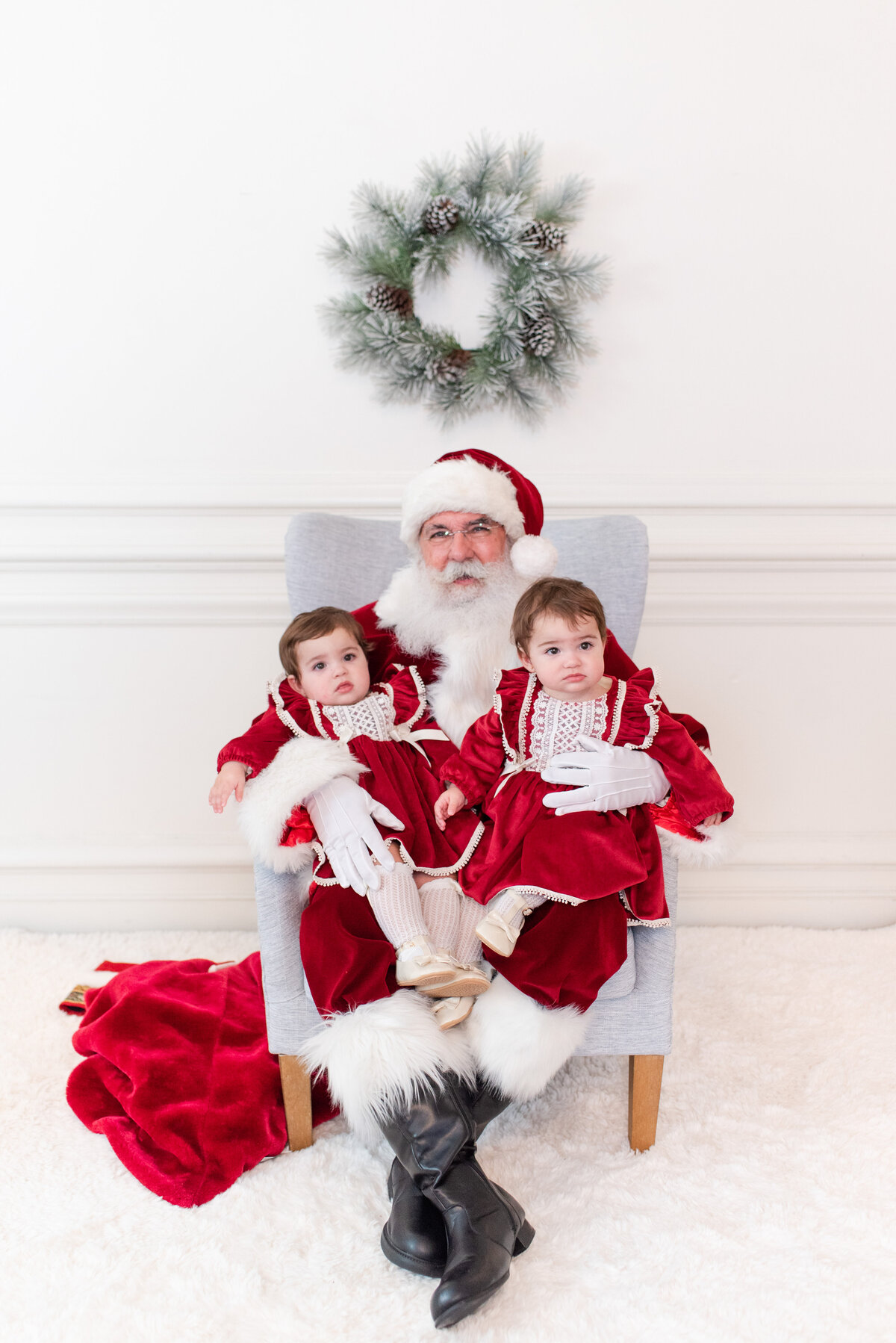 santa holding twin babies  toddler siblings brother and sister jumping on the bed with snow and pajamas by miami christmas mini session photographer msp