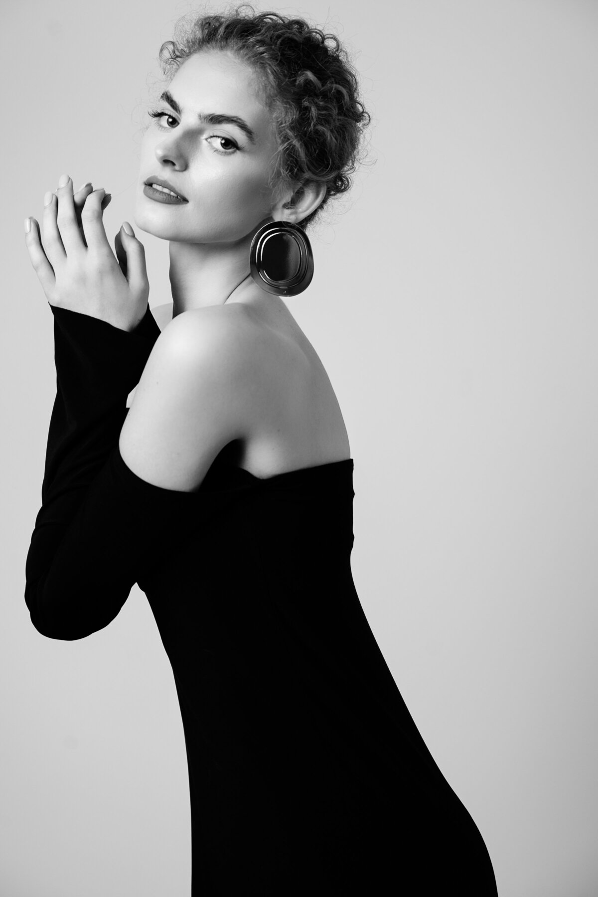 A young woman with her hair up wearing a black strapple dress with long sleeves