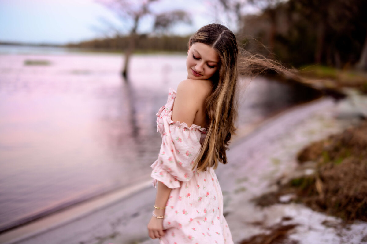 Senior girl flipping her hair in the breeze in a natural light session in Winter Garden, Florida