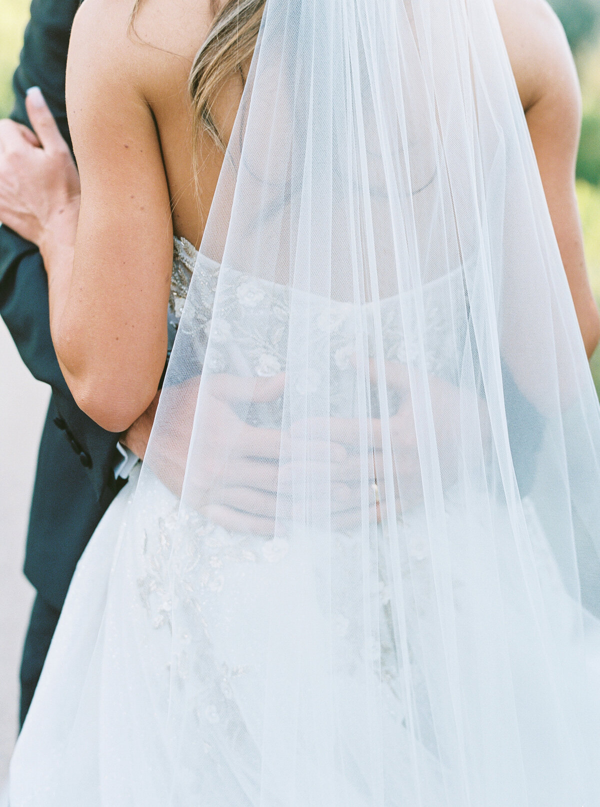 A stunning close-up of the bride and groom wrapped in an intimate embrace beneath a flowing veil. This fine art wedding photograph captures the elegance, romance, and timeless beauty of a luxury wedding moment.