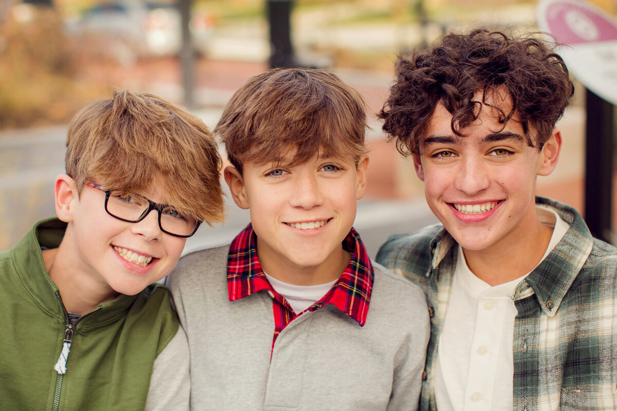 A headshot of three teenage  brothers smiling at the camera.