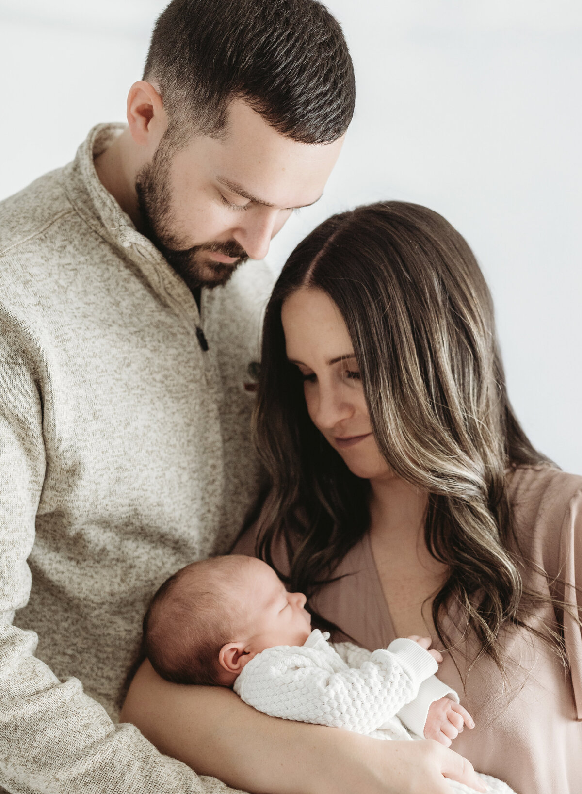 Parents holding their newborn together and smiling, captured during a warm and intimate family photography session in Kansas City.