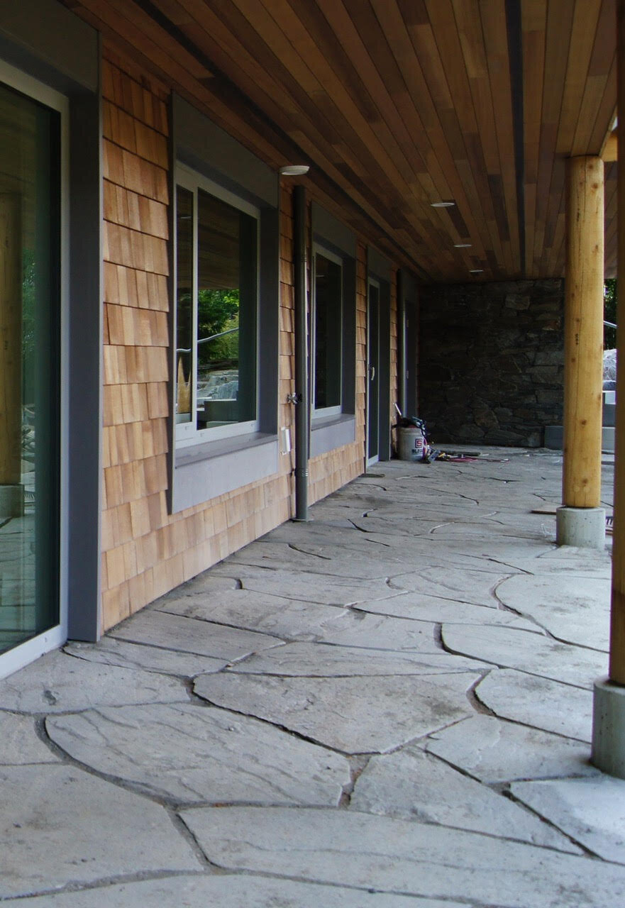 Home exterior design with cedar shingles, grey trim, and stone patio