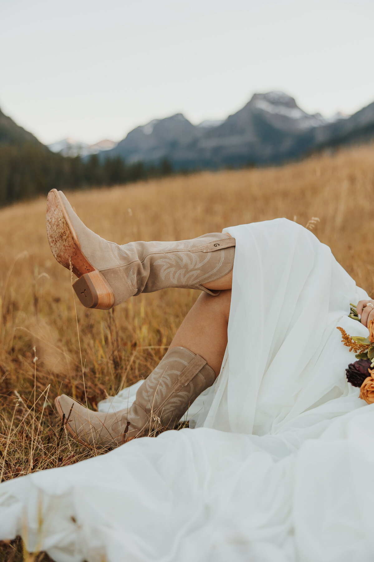 Detail photo of a bride’s cowgirl boots standing in a Montana field.